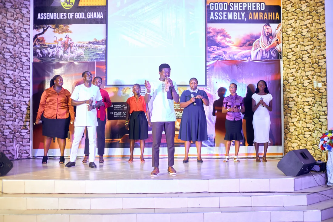 A group standing on the stage beneath event posters